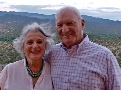 Jim & Florence Bassett Smiling In Front of A Mountain Range