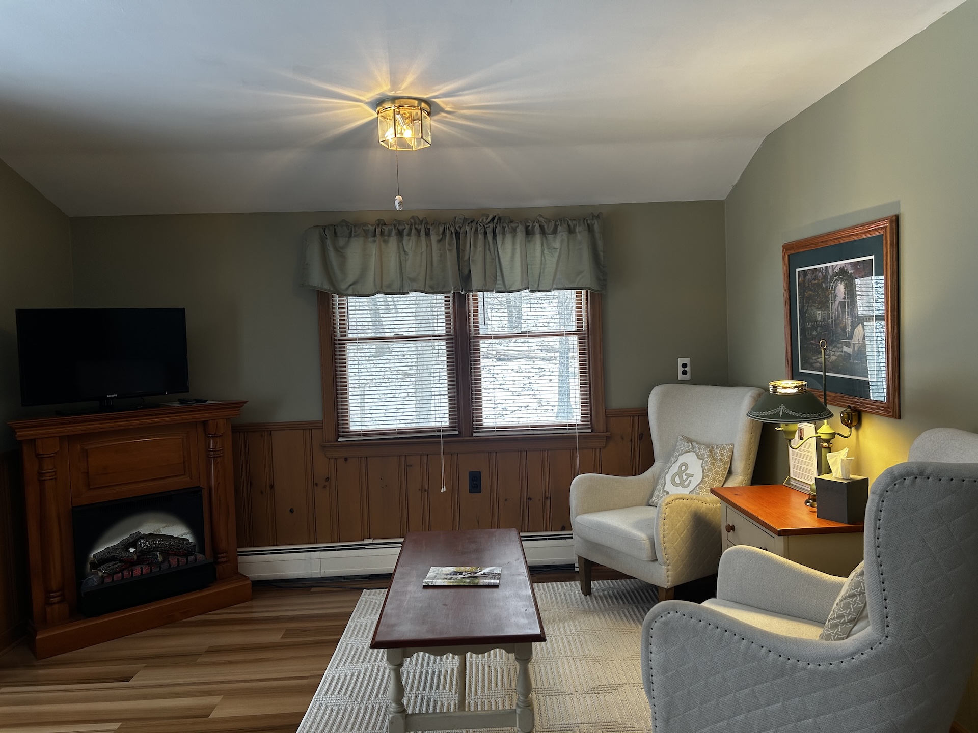 Room 8 Living Area featuring two beige chairs, a coffee table, an electric fireplace, and television.