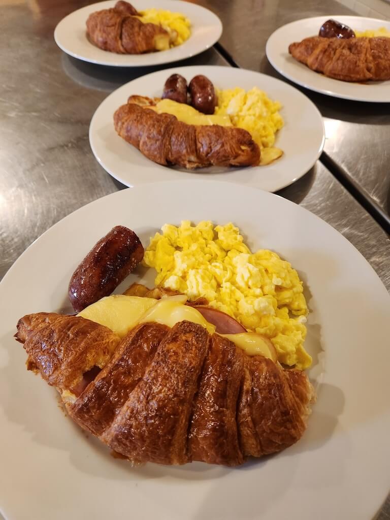 Croissant stuffed with apple, canadian bacon, and gruyere cheese. Accompanied by scrambled eggs and sausage.